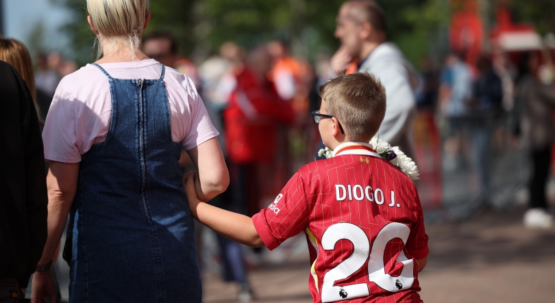 Imagem de Bandeira a meia haste, camisolas e flores junto a Anfield Road